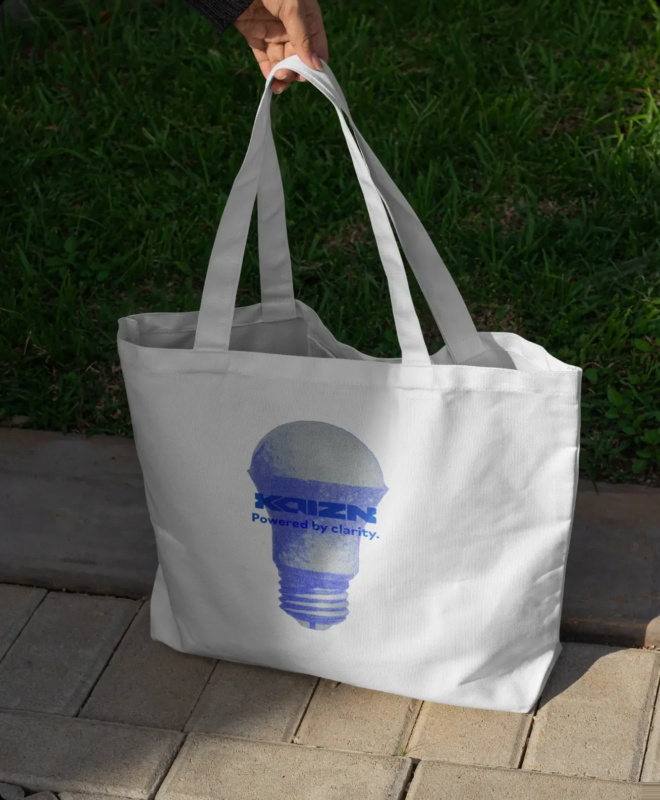A canvas tote carrying the bulb mark, held at arm’s length