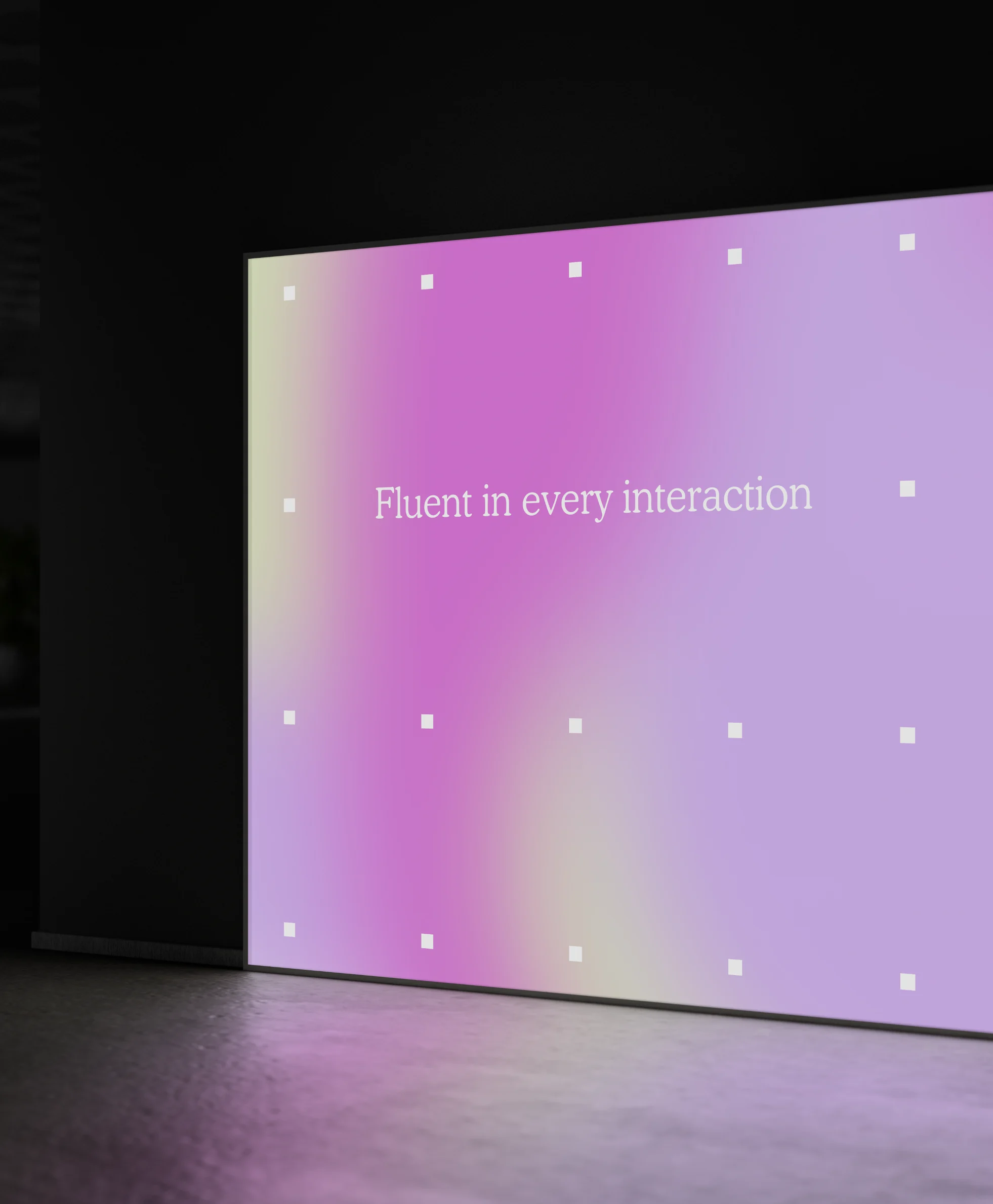 A gradient wall reading “Fluent in every interaction” in a dark room